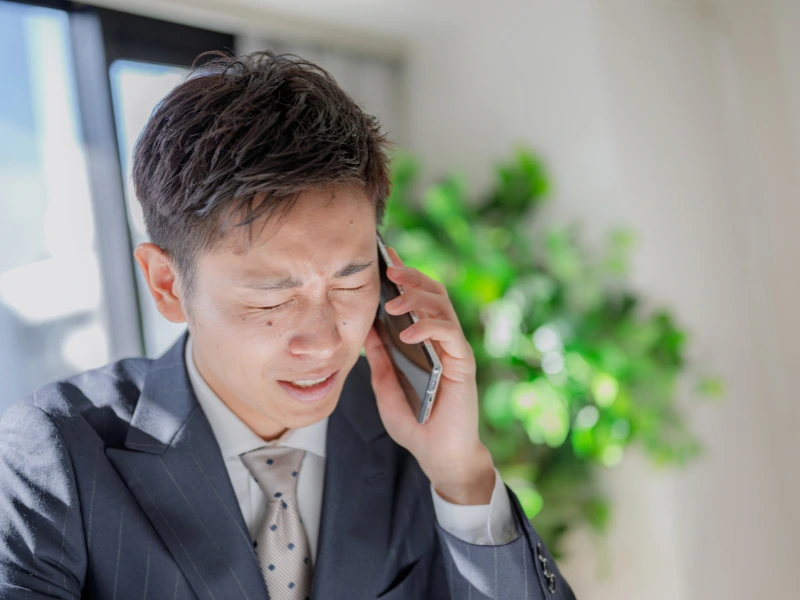 カスハラの電話に困った表情で応対する男性社員